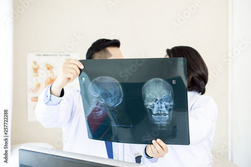 doctor examining x-ray film of Skull on white background - medical concept