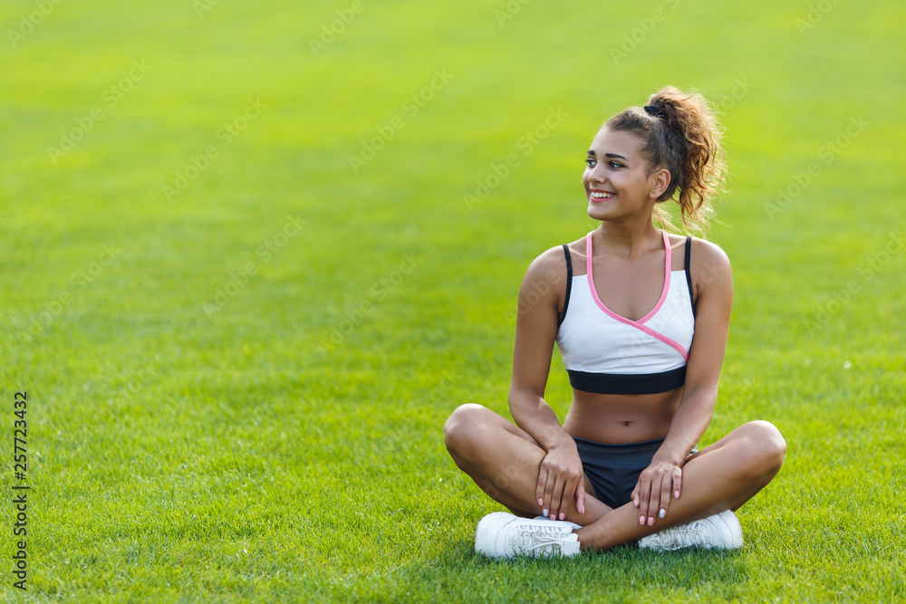 Young happy girl with curly hair in sportswear sitting in the lotus position Young happy girl with curly hair in sportswear sitting in the lotus position
