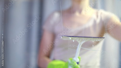 the woman washes a window. Splashes soapy water on the glass. Cleans the glass from dirt.