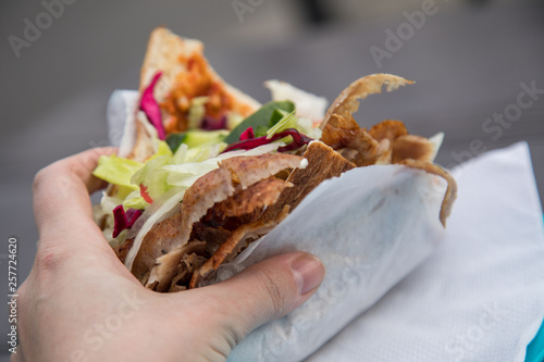 Frau isst Döner im Fladenbrot mit Salat und Kalb Fleisch draußen an Imbiss Bude photo