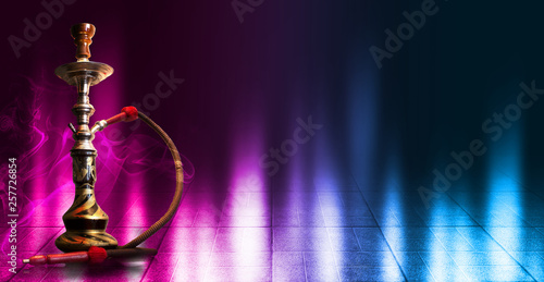Hookah smoking on a dark abstract background. Hookah on a concrete background, neon lights, blurred night lights, bokeh