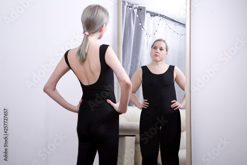 the girl looks at her reflection in the mirror. Think yourself fat. the causes of anorexia and bulimia © tatyanadjemileva