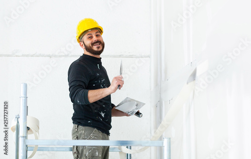 Valokuva worker plastering gypsum board wall.