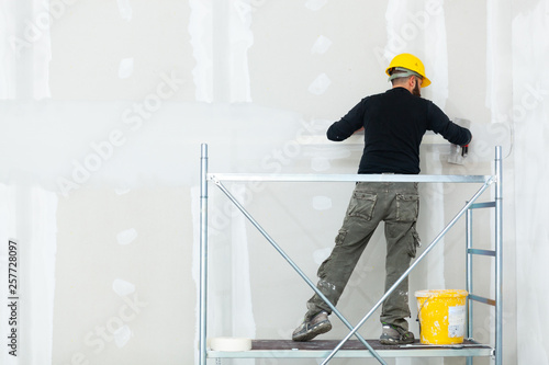 Valokuva worker plastering gypsum board wall.