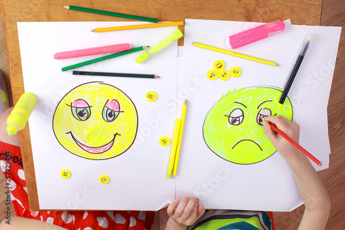 the development of emotional intelligence. child psychology. girl and boy depict different emotions. the girl and the boy draw happy and sad emoticons