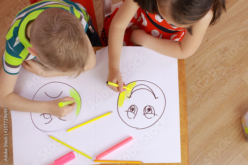 the development of emotional intelligence. child psychology. girl and boy depict different emotions. the girl and the boy draw happy and sad emoticons photo