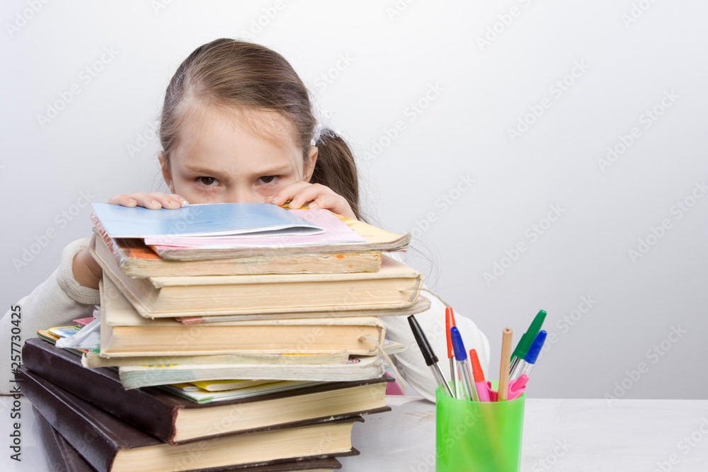Girl doing homework. The child was tired of congestion at the school. big burden on students. overloaded child Girl doing homework. The child was tired of congestion at the school. big burden on students. overloaded child