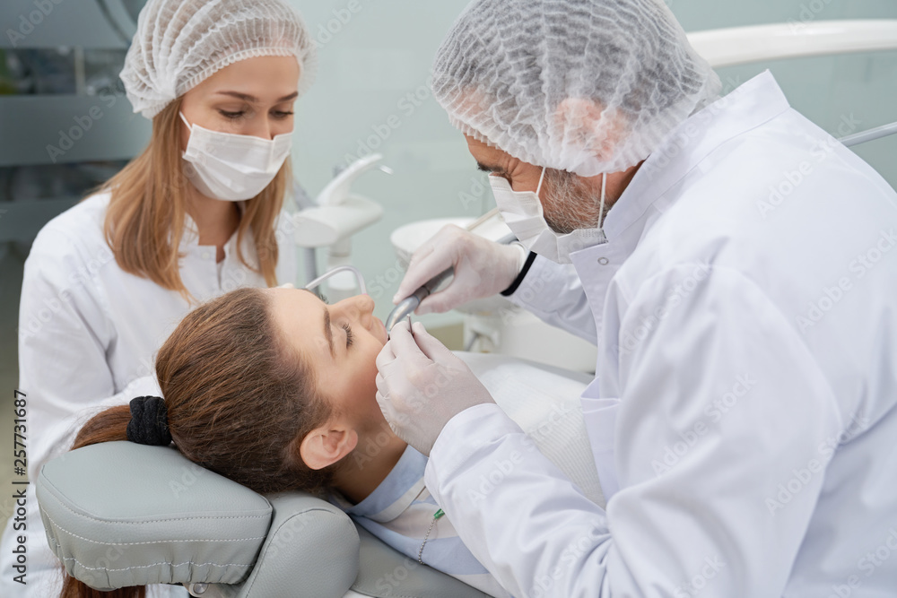 Dentist and assistant having woman's teeth done. Dentist and assistant having woman's teeth done.