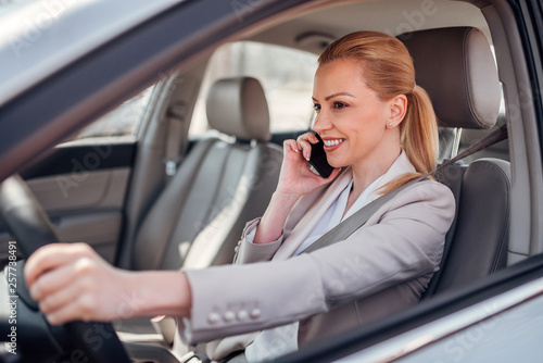 Businesswoman driving and talking on smartphone. © bnenin