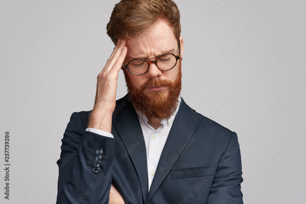 Stressed red bearded businessman rubbing forehead Stressed red bearded businessman rubbing forehead