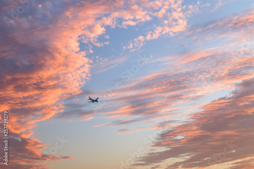 Airplane flying in the cloudy sunset sky. Travel transport airline sky background concept. Copy space.