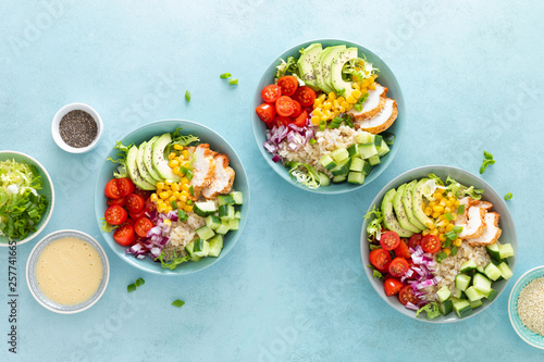 Lunch bowls with grilled cgicken meat, rice and fresh salad of avocado, cucumbers, corn, tomato and onion