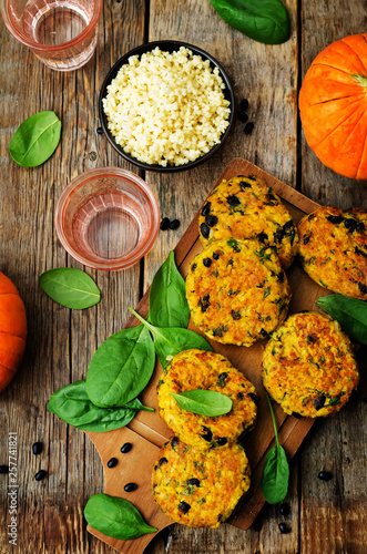 black bean millet pumpkin burgers with spinach leaves on a wood background