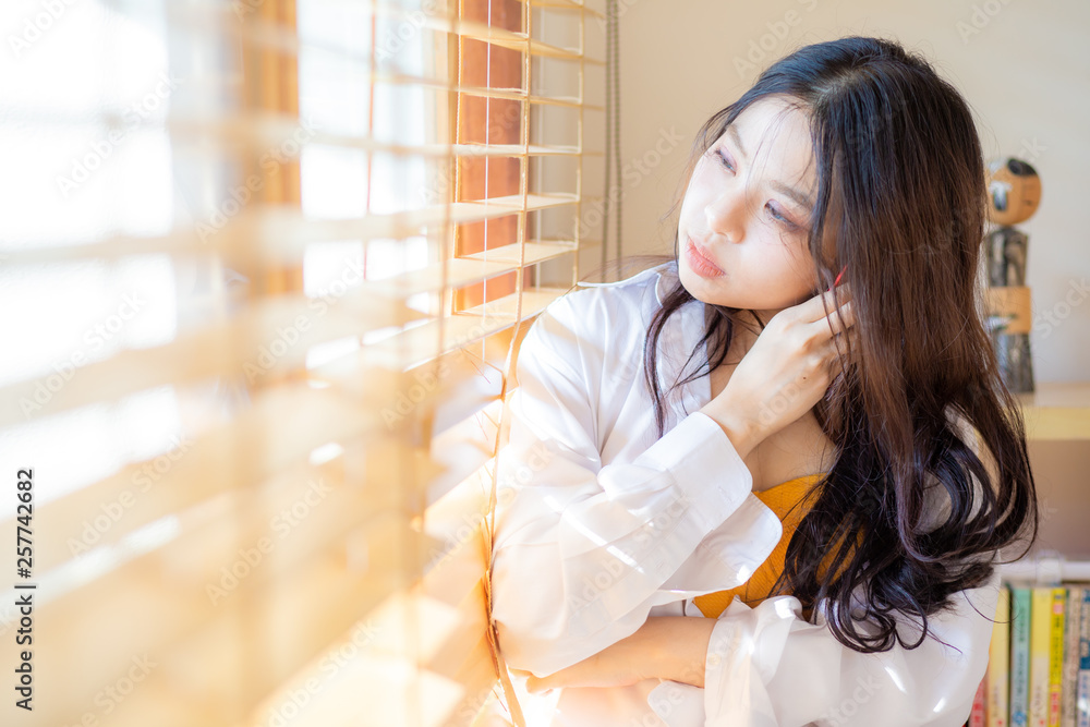 Beautiful women standing near window with sunset light Beautiful women standing near window with sunset light