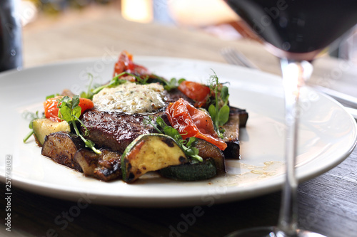 Entrecote steak with herb butter and grilled vegetables served with a glass of red wine.