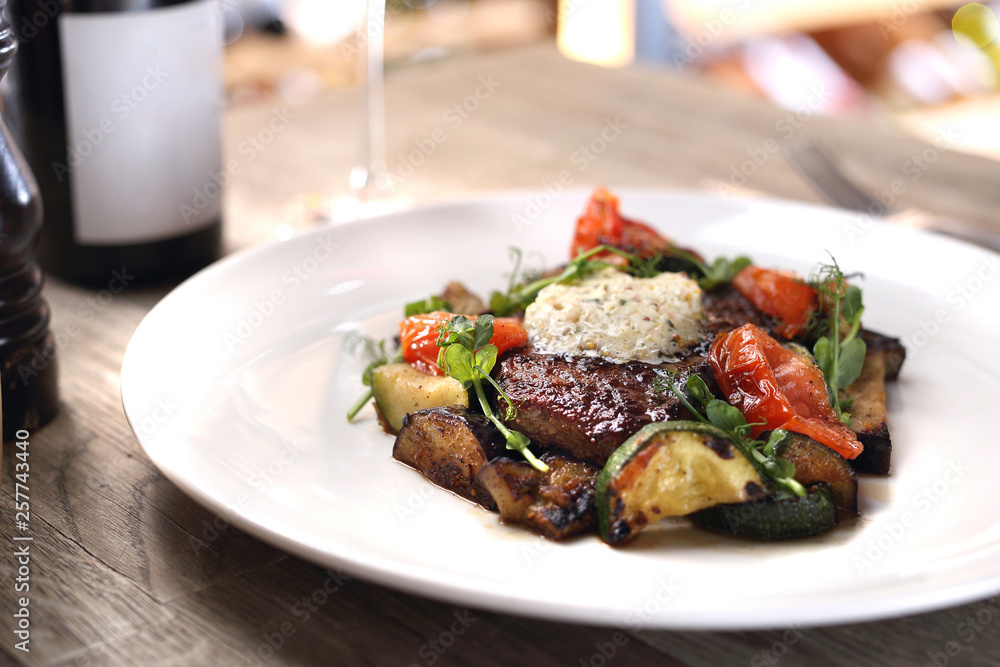 Grilled steak of entrecote with herb butter and grilled vegetables served on a white plate. Grilled steak of entrecote with herb butter and grilled vegetables served on a white plate.