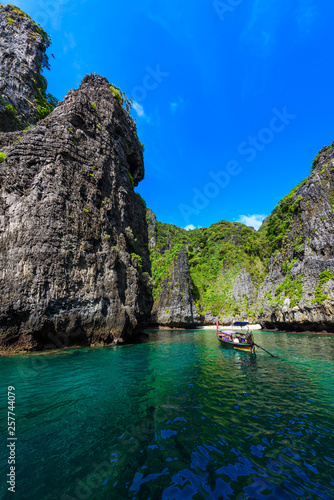 Wang Long Bay with crystal turquoise water, Tropical island Koh Phi Phi Don, Krabi Province, Thailand - Long boat in beautiful lagoon with rocks covered with a plants