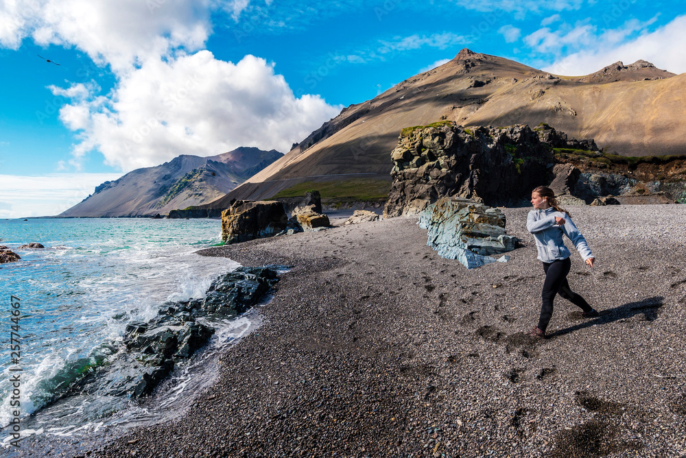 Girl teenager is on the Fauskasandur beach in the eastern Iceland. Maelifell hill is at background. Girl teenager is on the Fauskasandur beach in the eastern Iceland. Maelifell hill is at background.