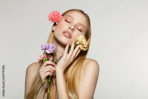 Spring blonde girl with closed eyes holding flowers in hands