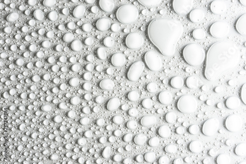 Droplets of water on a white, matte background illuminated with a delicate light.