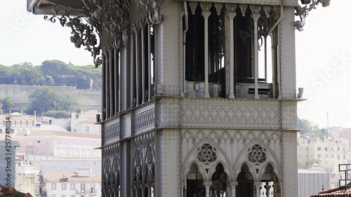 Close-up view famous Santa Justa Lift tower in Lisbon. Panoram shot from bottom to top facade ancient tower decorated forget metal on background city buildings in sunny day