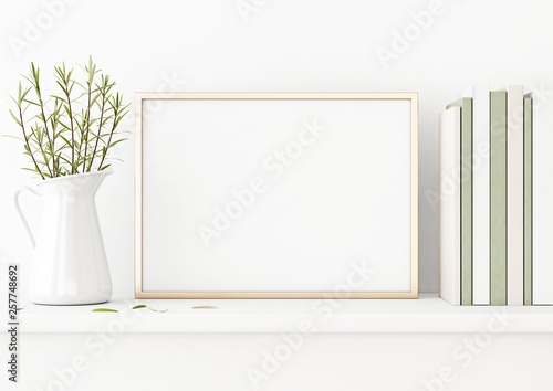 Horizontal poster mockup with golden metal frame standing on table and decorated with jug, green plants and pile of books on empty white wall background. 3D rendering, illustration.