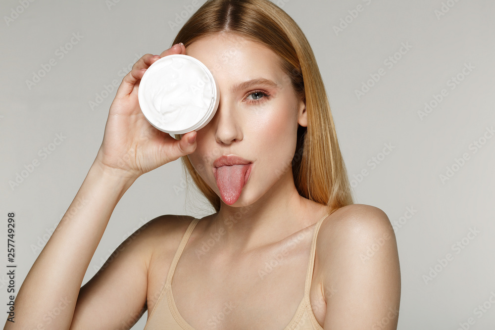 Amazing girl with natural perfect skin with bare shoulders hide one eye with cream tube Amazing girl with natural perfect skin with bare shoulders hide one eye with cream tube