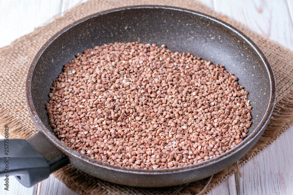 Buckwheat grain in the pan on a table Buckwheat grain in the pan on a table