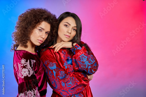 Girls in red dresses with traditional flower ornament.