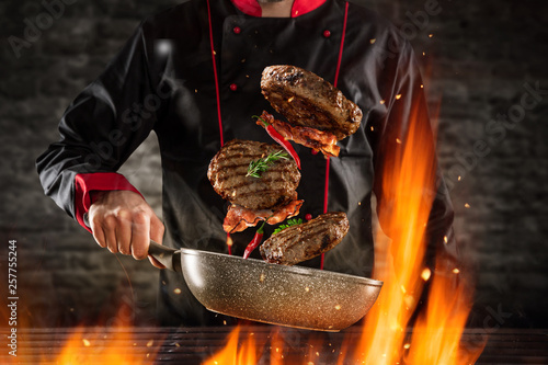 Closeup of chef throwing hamburger steaks