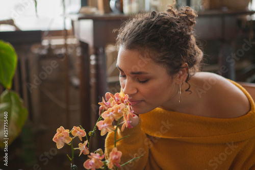 Close-up of woman with eyes closed smelling flowers while sitting at home