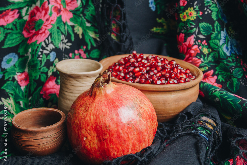 pomegranate grains in a ceramic bowl on a vintage fabric background, pomegranate fruit, ceramic jug, ceramic plate, ethnic shawl, Romma shawl, still life pomegranate grains in a ceramic bowl on a vintage fabric background, pomegranate fruit, ceramic jug, ceramic plate, ethnic shawl, Romma shawl, still life