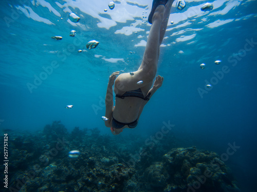 Freediver young woman swims underwater with snorkel and flippers