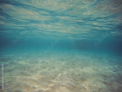picture taken underwater. Clear blue water and white sand.