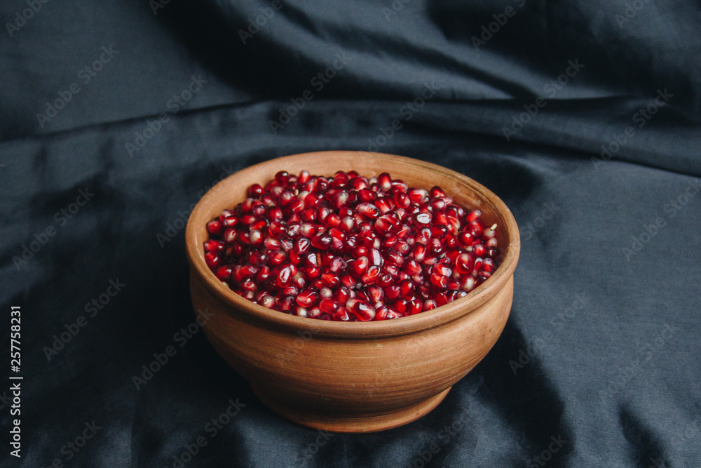 pomegranate grains in a ceramic bowl on a black fabric background, pomegranate fruit, ceramic jug, ceramic plate, isolated still life close up pomegranate grains in a ceramic bowl on a black fabric background, pomegranate fruit, ceramic jug, ceramic plate, isolated still life close up