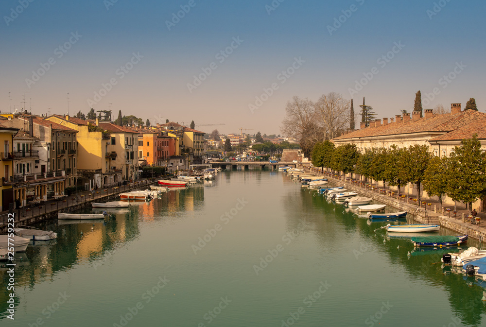 High angle view of the canal of Peschiera del Garda with the typical colored houses and moored boats, Veneto, Italy 