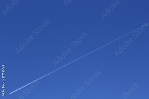 Airplane white trail in a pale blue sky