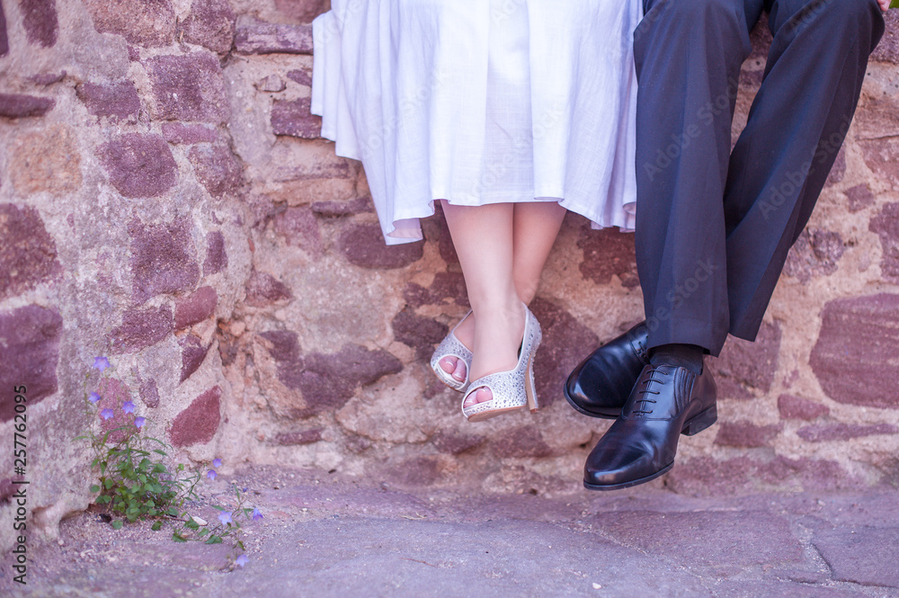 Schuhe von Braut und Bräutigam, die auf einer Mauer sitzen