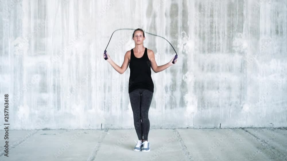 young fitness woman jumping rope in empty industrial building. young fitness woman jumping rope in empty industrial building.