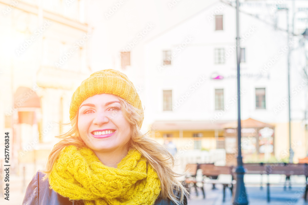 Portrait of Happy young adult woman smiling with teeth smile outdoors on city street weating yellow colors winter clothes and knitted scarf. Portrait of Happy young adult woman smiling with teeth smile outdoors on city street weating yellow colors winter clothes and knitted scarf.