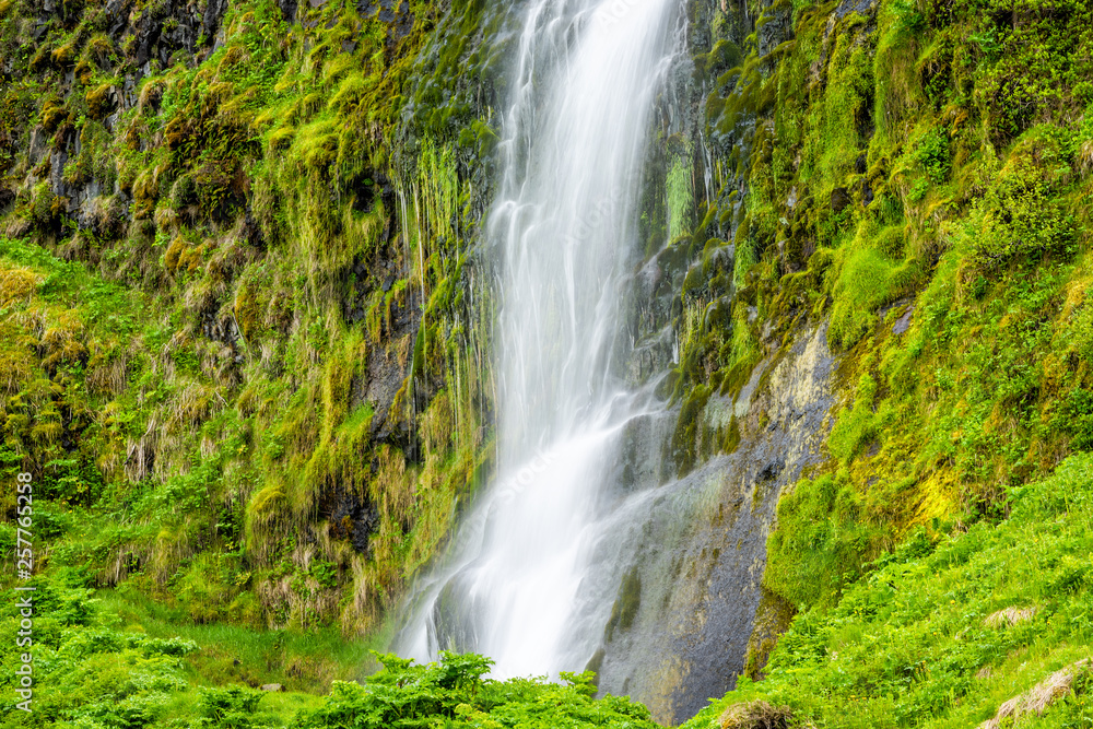 Small waterfall closeup by Seljalandsfoss, Iceland with white water falling off cliff top long exposure in green mossy summer rocky landscape Small waterfall closeup by Seljalandsfoss, Iceland with white water falling off cliff top long exposure in green mossy summer rocky landscape