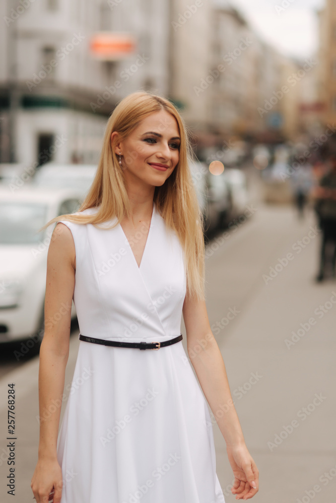 Beautiful blond hair woman in white dress dance in the centre of the city
