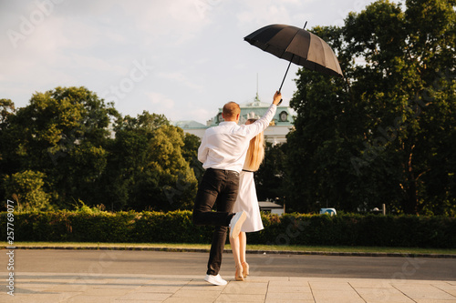 Young couple jump up with black upbrella. Lovely cuople have fun © Aleksandr