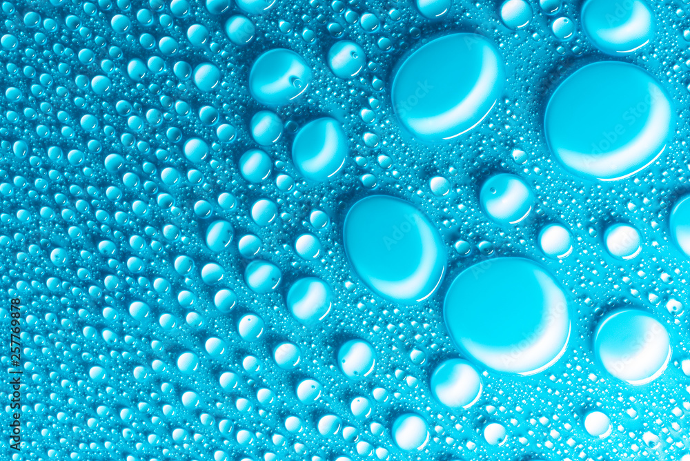 Droplets of water on a blue, matte background illuminated with a delicate light. Droplets of water on a blue, matte background illuminated with a delicate light.