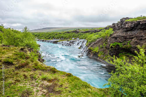 Long exposure smooth colorful vibrant blue aqua turquoise water waterfall cascades Hraunfossar Lava Falls in Iceland, landscape view