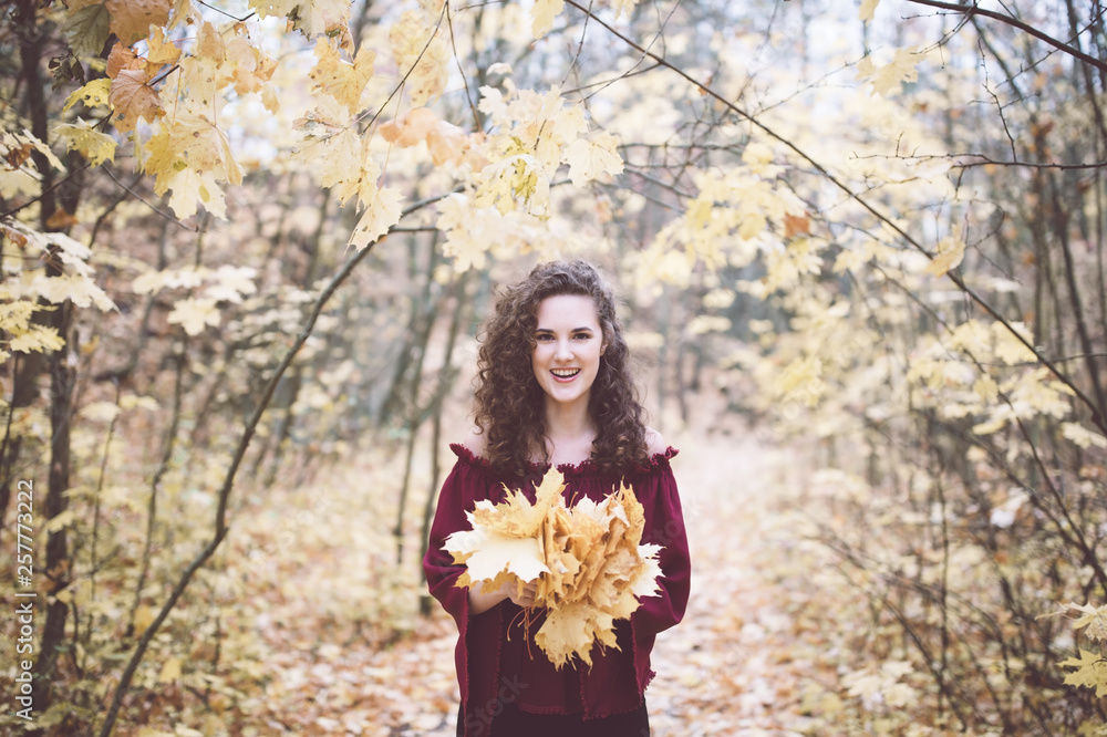 Happy girl in an atumn park holding maple leaves Happy girl in an atumn park holding maple leaves