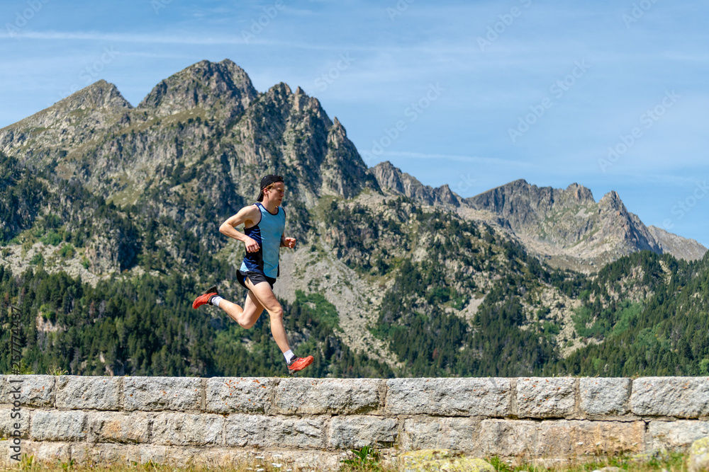 Male athlete running across a stone wall in the mountains