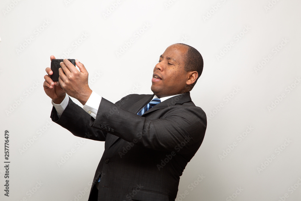African American Business Man Uses Smart phone on Light Gray Background African American Business Man Uses Smart phone on Light Gray Background