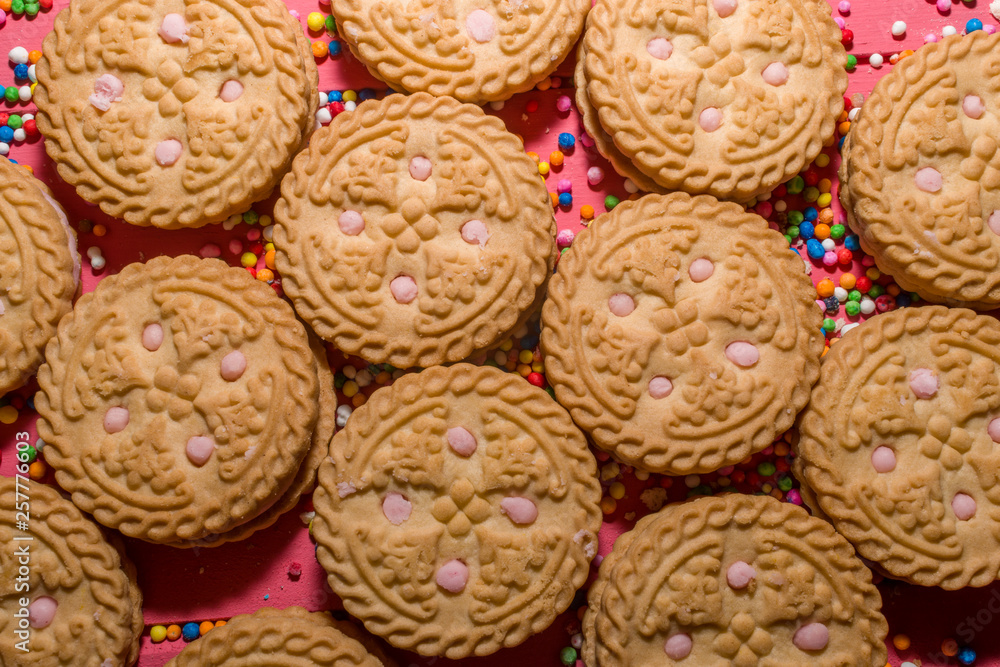 strawberry-flavored cream-filled cookies in the foreground on pink colored wooden strawberry-flavored cream-filled cookies in the foreground on pink colored wooden