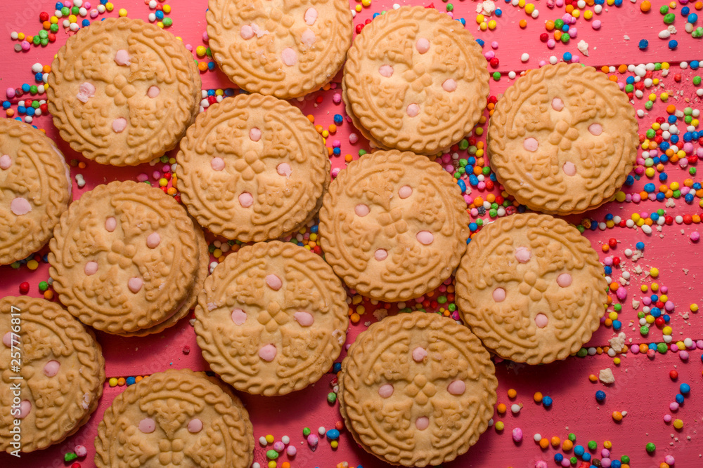 strawberry-flavored cream-filled cookies in the foreground on pink colored wooden strawberry-flavored cream-filled cookies in the foreground on pink colored wooden